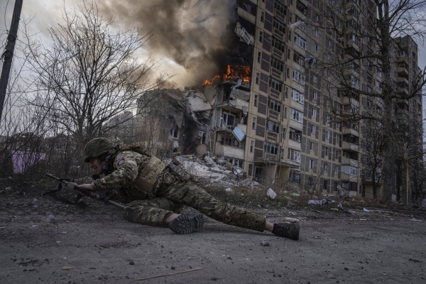 ▲우크라이나 경찰관이 러시아군 공습으로 불타는 동부 아우디이우카의 한 아파트 앞에서 몸을 숨기고 있다. 아우디이우카(우크라이나)/AP연합뉴스
