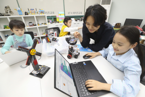 ▲선생님이 어린 학생들에게 KT AI 코디니를 이용해 코딩과 하드웨어 융합 교육을 진행하고 있다. (사진 제공= KT)