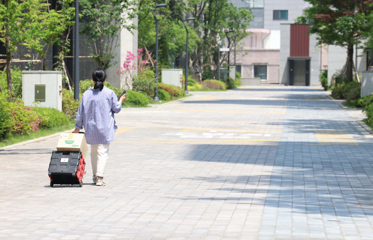 ▲11일 경기 수원시의 한 대단지 아파트에서 입주민이 택배를 짐수레로 가져가고 있다. 지난 1일 이 아파트 입주민들이 안전사고 우려 등으로 택배 차량의 지상출입을 금지하고 지하주차장만 이용할 것을 결정하자 기사들은 배송 차량 높이 탓에 지하주차장 진입이 불가능하다며 문앞 배송을 거부, 갈등이 빚어지고 있다. 신태현 기자 holjjak@