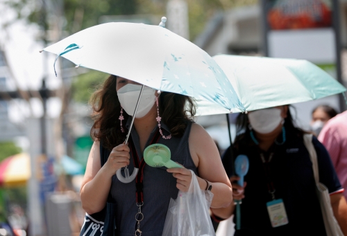 ▲태국 방콕에서 한 여성이 무더위를 피하기 위해 양산을 쓰고 휴대용 선풍기를 든 채 거리를 걷고 있다. 방콕/EPA연합뉴스
