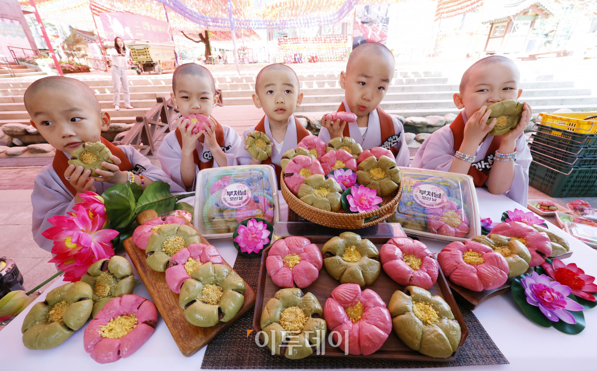 ▲23일 서울 종로구 조계사에서 단기출가 과정 '보리수 새싹학교' 동자승들이 부처님 오신날을 맞아 출시한 신세계푸드 '연꽃단팥빵'을 선보이고 있다. 우유, 계란, 버터 없이 100% 식물성 재료로 만든 연꽃닽팥빵은 백년초와 연잎 가루로 색을 내고 불교의 6가지 수행덕목을 상징하는 '육바라밀'을 6개의 꽃잎 모양에 담았다. 조현호 기자 hyunho@