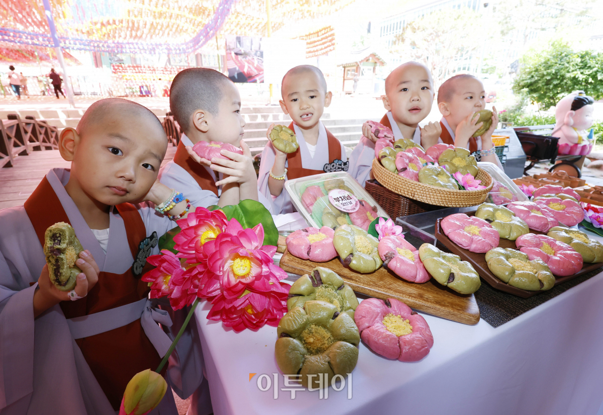 ▲23일 서울 종로구 조계사에서 단기출가 과정 '보리수 새싹학교' 동자승들이 부처님 오신날을 맞아 출시한 신세계푸드 '연꽃단팥빵'을 선보이고 있다. 우유, 계란, 버터 없이 100% 식물성 재료로 만든 연꽃닽팥빵은 백년초와 연잎 가루로 색을 내고 불교의 6가지 수행덕목을 상징하는 '육바라밀'을 6개의 꽃잎 모양에 담았다. 조현호 기자 hyunho@