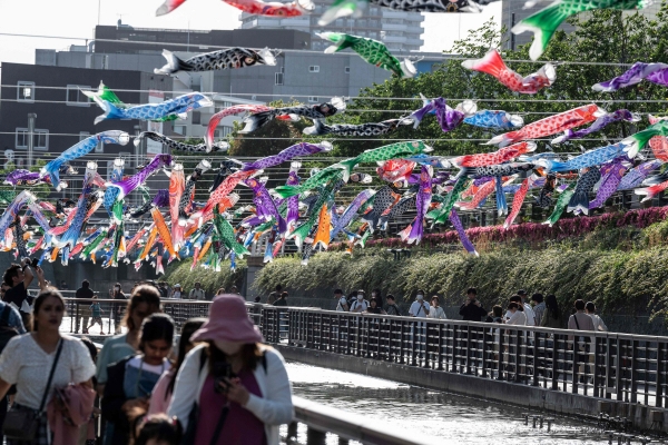 ▲일본 도쿄에서 5일 방문객들이 형형색색의 잉어 깃발 ‘고이노보리’가 걸린 강가를 걷고 있다. 도쿄/AFP연합뉴스
