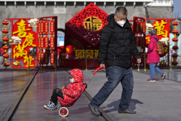 ▲중국 베이징에서 한 남성이 지난 1월 춘제(중국 설) 장식으로 꾸며진 인기 관광지인 치안먼 거리에서 아이와 함께 길을 가고 있다. 베이징/AP뉴시스