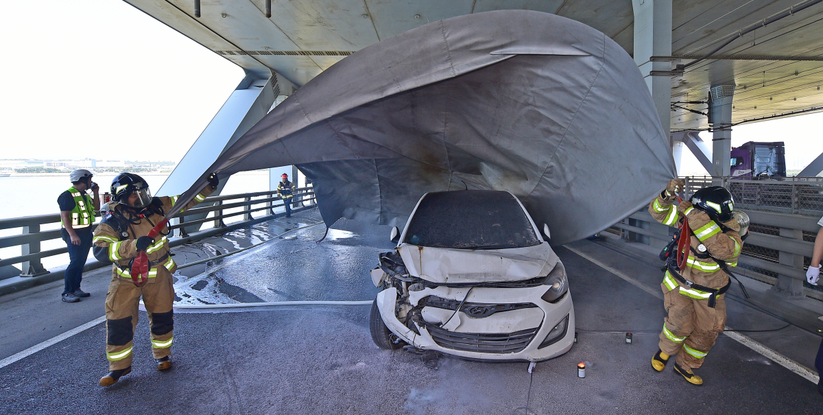 ▲13일 오후 인천시 중구 신공항하이웨이 영종방면 영종대교 하부에서 열린 '2023 재난대응 안전한국훈련'에서 안개상황을 가정해 발생한 추돌사고 현장에 급파된 소방대원들이 질식소화덮개를 이용해 차량화재 진압을 시도하고 있다. 신태현 기자 holjjak@