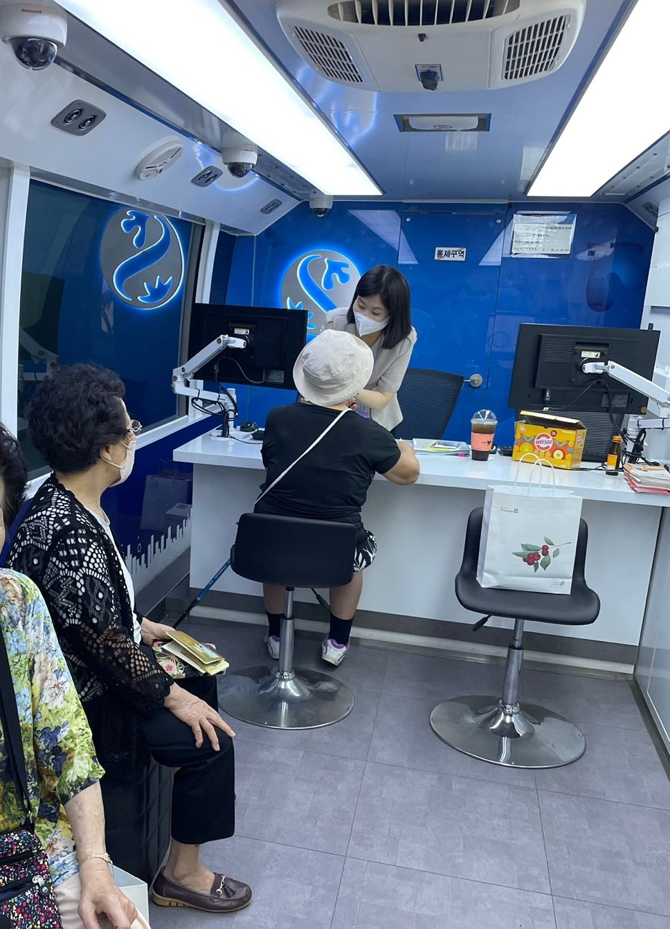 ▲양천어르신종합복지관 고객들이 26일 신한은행의 '찾아가는 시니어 이동점포;'를 방문해 은행 업무를 보고 있다. (사진제공=신한은행)