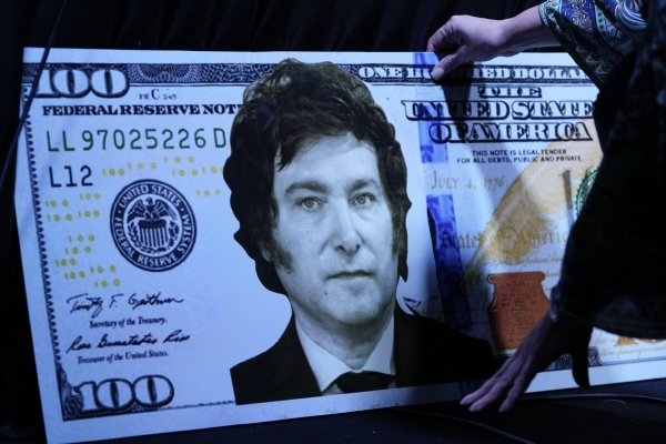 ▲100달러 지폐에 아르헨티나 대선 주자 하비에르 밀레이 얼굴사진을 합성한 그림판이 놓여져 있다. AP뉴시스
