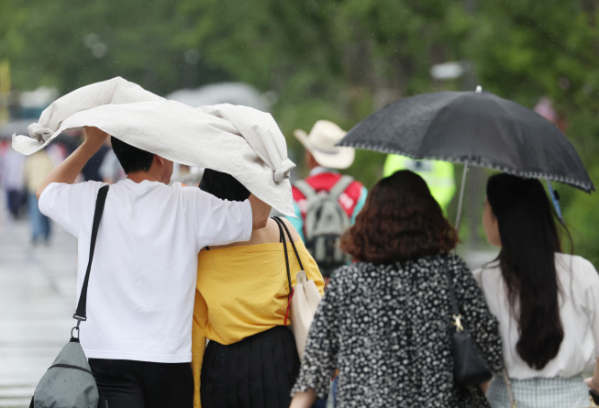 ▲6일 광화문광장을 지나는 시민들이 갑자기 쏟아지는 비를 옷으로 막으며 걸어가고 있다. (연합뉴스)