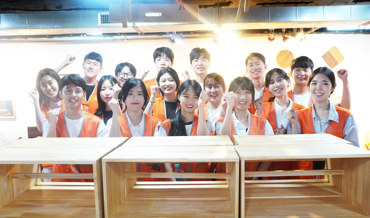 ▲27일 용산구에 위치한 해쉬더우드 공방에서 코스콤 신입직원들이 DIY 제작 봉사활동을 진행하고, 기념촬영을 찍고 있다.  (사진=코스콤)