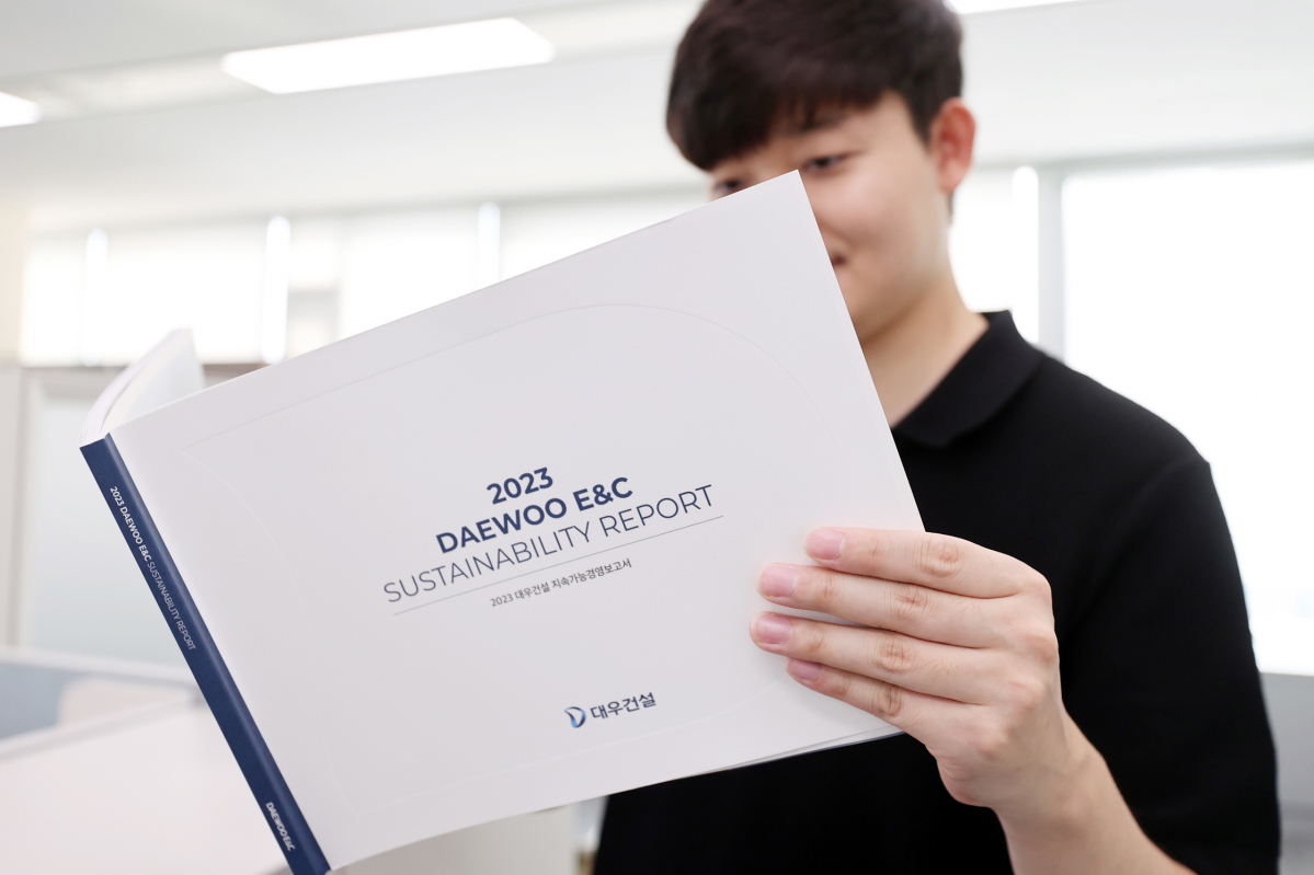 ▲대우건설 직원이 '2023 대우건설 지속가능경영보고서'를 보고 있다 (자료제공=대우건설)