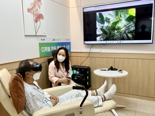 ▲디지털 치유 정원 2호점이 설치된 '서울재활병원'에 입원 중인 환자가 국립세종수목원을 촬영한 VR 영상을 직접 체험하고 있다 (사진제공=두나무)
