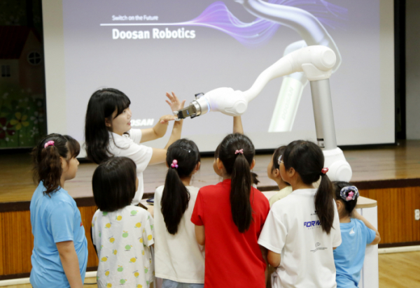 ▲두산로보틱스 임직원이 아이들에게 협동로봇의 개념과 기본적인 작동 과정 등을 교육하고 있다. (사진제공=두산로보틱스)