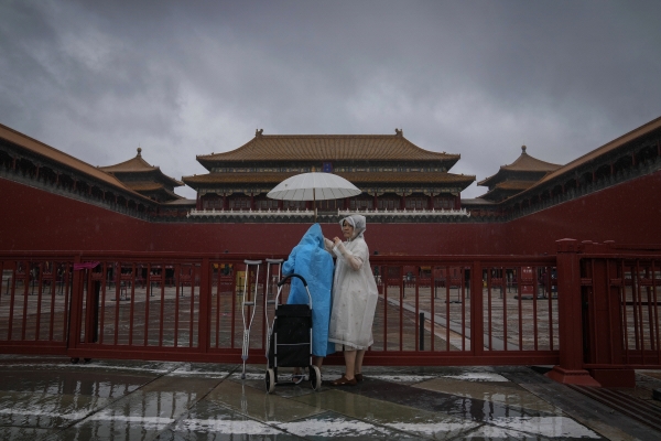 ▲중국 자금성의 닫힌 출입문 앞에서 관광객이 우산을 쓴 채 서 있다. 베이징/AP연합뉴스
