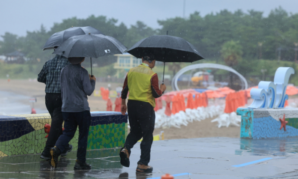 ▲30일 오전 제주 이호해수욕장에서 우산을 든 이들이 산책하고 있다. (연합뉴스)