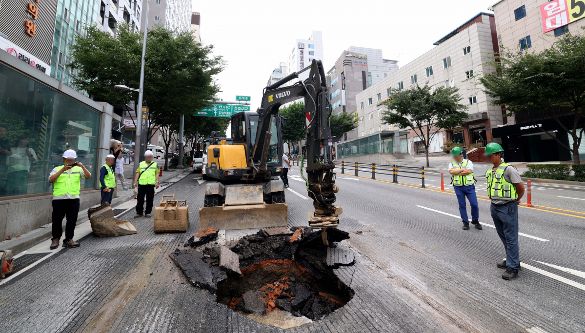 ▲12일 서울 강남구 봉은사로 한복판에서 지름 1m, 깊이 3m 가량 땅꺼짐(싱크홀) 현상이 발생한 가운데 관계자들이 복구작업을 하고 있다. 경찰과 강남구청에 따르면 이날 오전10시 45분께 서울 지하철 9호선 언주역 8번 출구 앞 도로에서 땅꺼짐 현상이 발생했다. 도로를 지나던 사다리차 바퀴가 구멍에 빠졌으나 인명 피해는 발생하지 않았다. 땅꺼짐 현상은 인근 상수도관 파손으로 지반이 약해짐에 따라 발생한 것으로 알려졌다. 신태현 기자 holjjak@