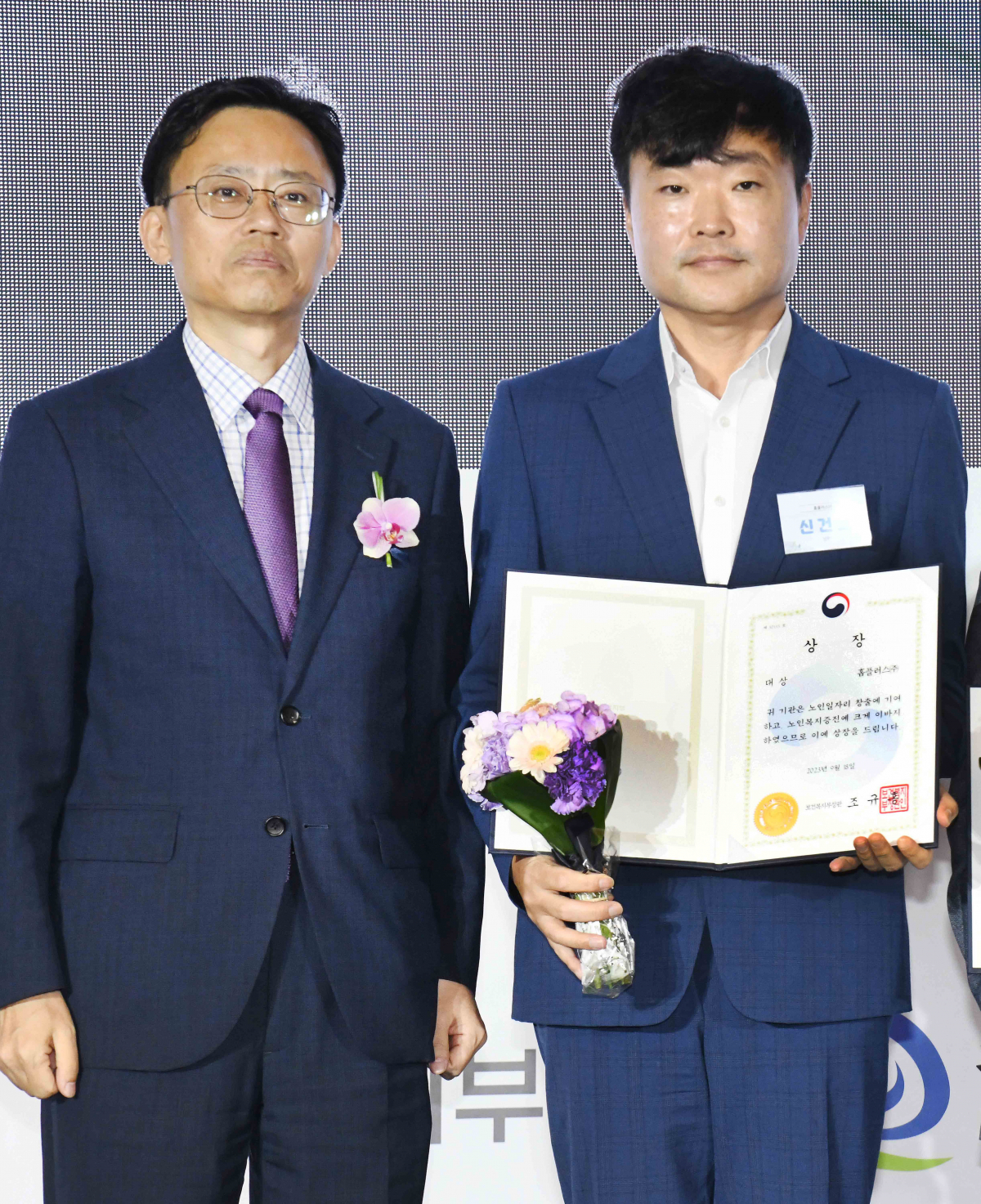 ▲18일 서울 성동구에서 열린 ‘2023 노인일자리 주간’ 기념식에서 신건호 홈플러스 대외정책총괄(오른쪽)이 최종균 보건복지부 인구정책실장과 기념 촬영을 하고 있다. (사진제공=홈플러스)