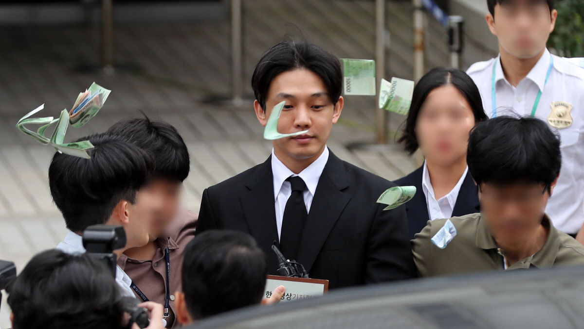 ▲배우 유아인(본명 엄홍식)이 21일 서울 서초구 서울중앙지법에서 열린 마약류 관리에 관한 법률 위반 등 혐의 구속 전 피의자 심문(영장실질심사)을 마친 후 대기 장소로 이동하는 중 한 시민이 “영치금으로 쓰라”며 돈을 뿌리고 있다. (뉴시스)
