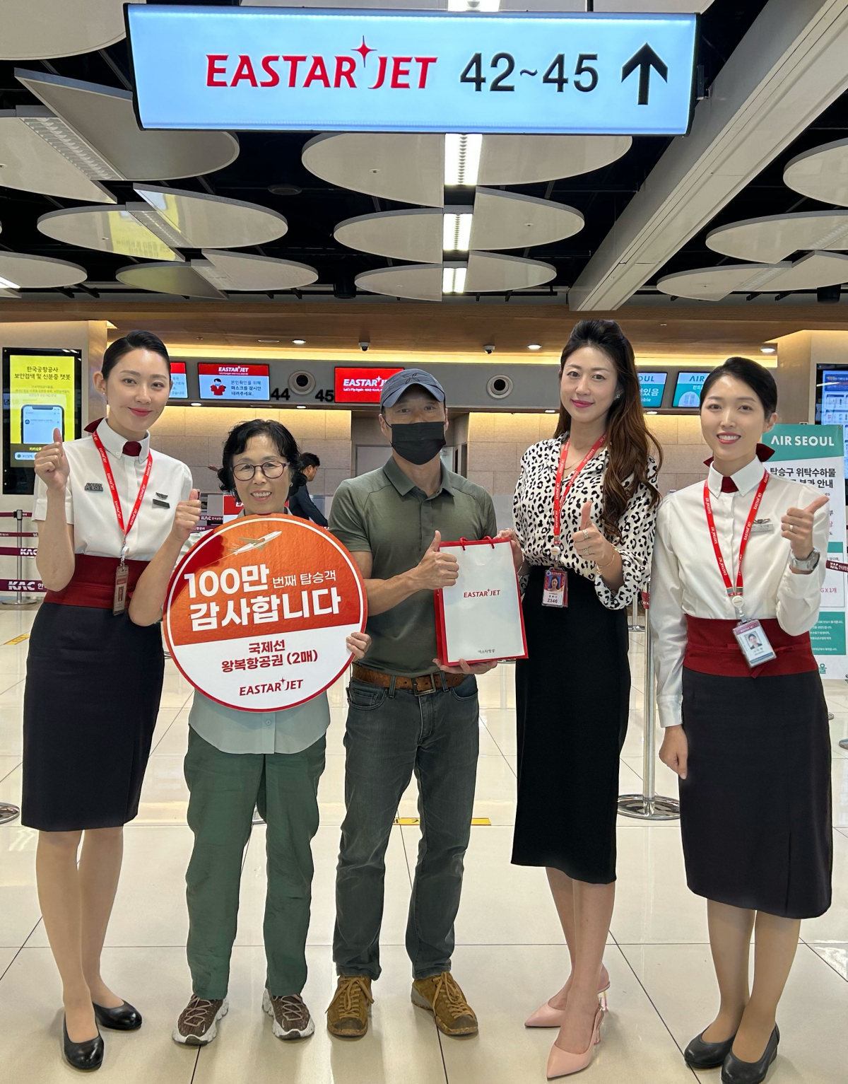 ▲이스타항공 권하나 김포지점장(오른쪽에서 두 번째)이 100만 번째 탑승객 최연주 씨와 어머니 신영순 씨께 항공권과 기념품을 나눠준 후 기념 촬영을 하고 있다. (사진제공=이스타항공)