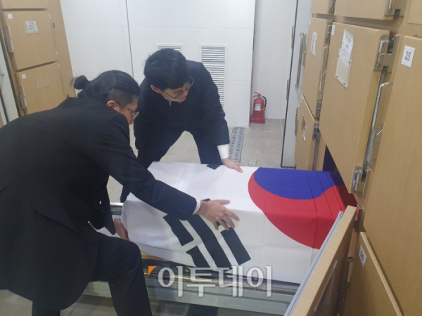 ▲을지대 장례지도학과 3학년 전관호(왼쪽) 씨와 윤주노(오른쪽) 씨가 을지대장례식장에서 실습을 하고 있는 모습. 두 사람은 이날 안치실에서 관을 꺼내 발인 나갈 준비를 했다. 관을 태극기로 덮은 이유는 고인이 국가유공자이기 때문이다. 국가유공자 사망시 국가보훈부는 태극기를 제공한다. (사진=송석주 기자)