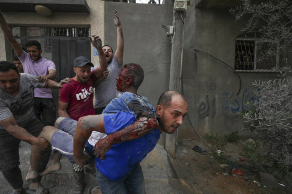 ▲11일(현지시간) 팔레스타인 가자지구 북부 자발리아에서 주민들이 이스라엘의 공습으로 다친 사람들을 옮기고 있다. 가자지구(팔레스타인)/AP뉴시스
