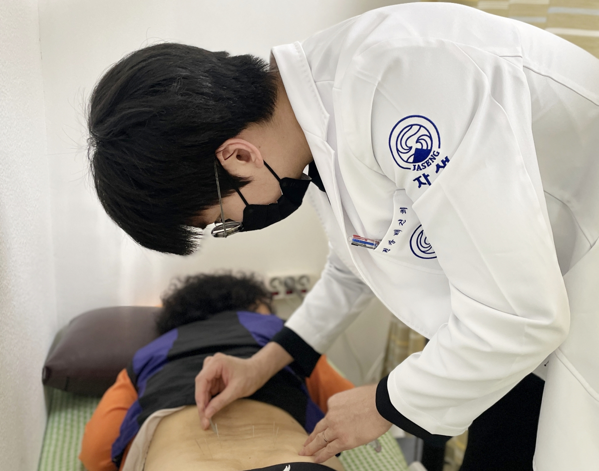 ▲의료진이 진료소를 찾은 노인에게 침치료를 실시하고 있다.