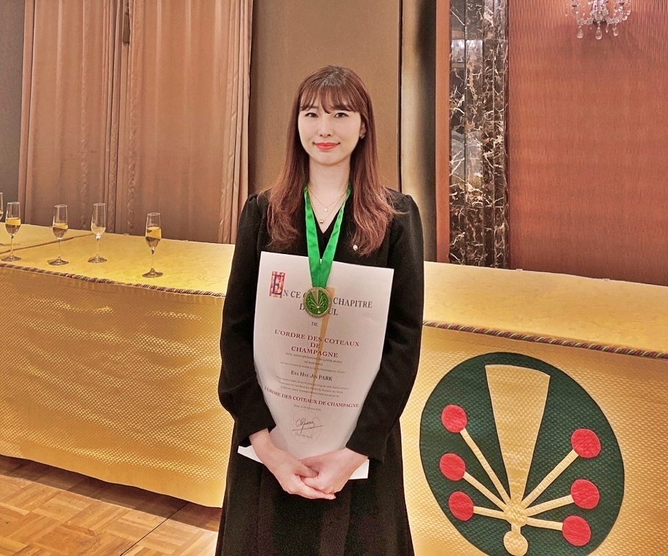 ▲박혜진 롯데슈퍼 와인 상품기획자가 26일 서울시 중구에 위치한 롯데호텔 서울 3층 사파이어룸에서 샴페인 기사 작위인 ‘담슈발리에’ 작위를 받고 기념촬영을 하고 있다. (사진제공=롯데쇼핑)