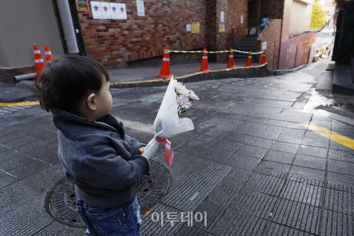 ▲10.29 이태원 참사 1주기인 29일 오전 서울 용산구 이태원 참사 골목 '10.29 기억과 안전의길'에서 한 어린이가 국화꽃을 들고 거리를 바라보고 있다. 조현호 기자 hyunho@