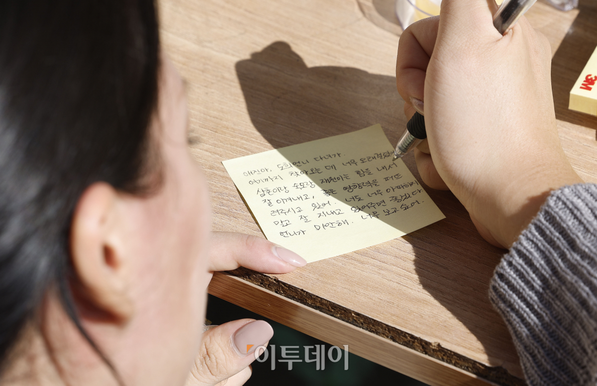 ▲10.29 이태원 참사 1주기인 29일 서울 용산구 이태원 참사 골목 '10.29 기억과 안전의길'에서 유가족 송도희 씨가 사촌동생인 신애진(당시 24세) 씨에게 추모 메시지를 작성하고 있다. 조현호 기자 hyunho@