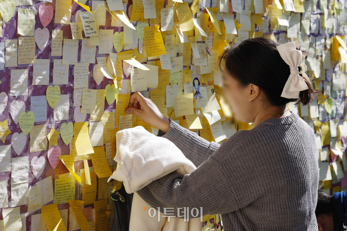 ▲10.29 이태원 참사 1주기인 29일 서울 용산구 이태원 참사 골목 '10.29 기억과 안전의길'에서 유가족 송도희 씨가 사촌동생인 신애진(당시 24세) 씨에게 작성한 추모 메시지를 외벽에 붙이고 있다. 조현호 기자 hyunho@