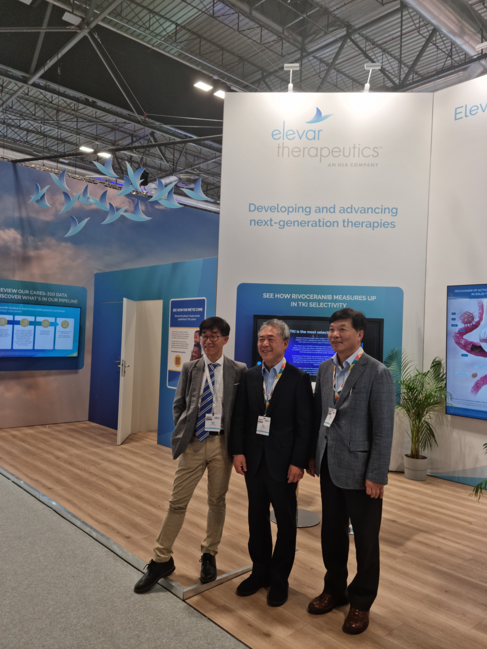 ▲ESMO 2023 행사장에 마련된 엘레바 홍보부스에서 장성훈 엘레바 COO(왼쪽부터), 정세호 엘레바 CEO, 한용해 HLB그룹 CTO가 기념촬영하고 있다. (사진제공=HLB)