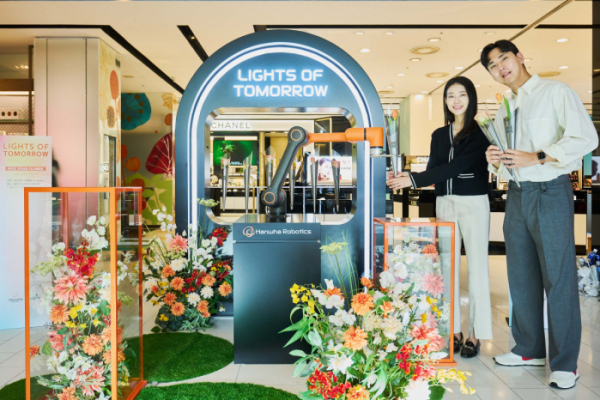▲갤러리아백화점 서울 명품관을 방문한 고객들이 로봇이 건네주는 꽃을 받고 있다. (사진제공=한화로보틱스)