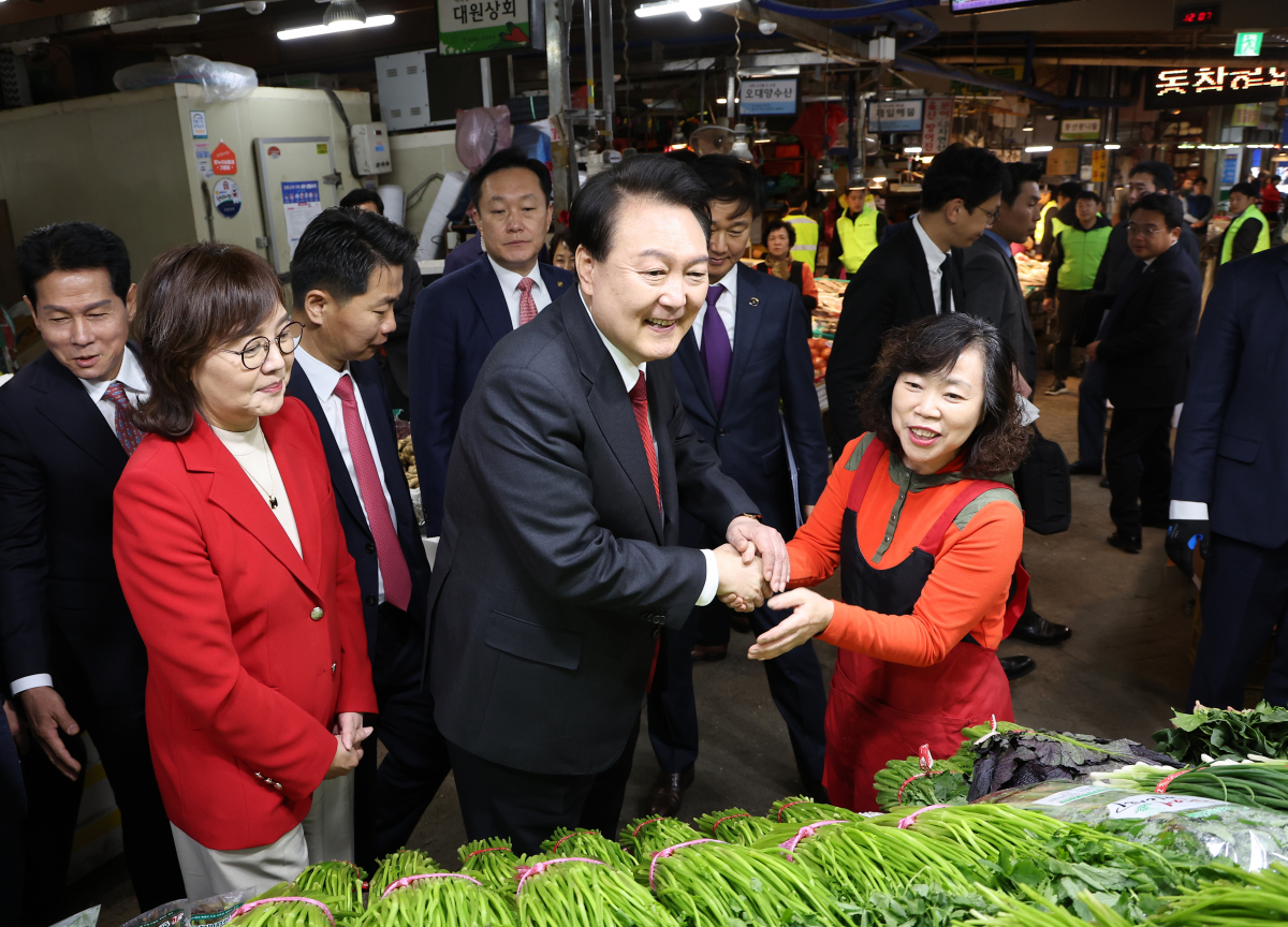 ▲윤석열 대통령이 7일 대구 북구 칠성종합시장을 방문, 미나리를 구매하며 시장 상인과 악수하고 있다. (연합뉴스)