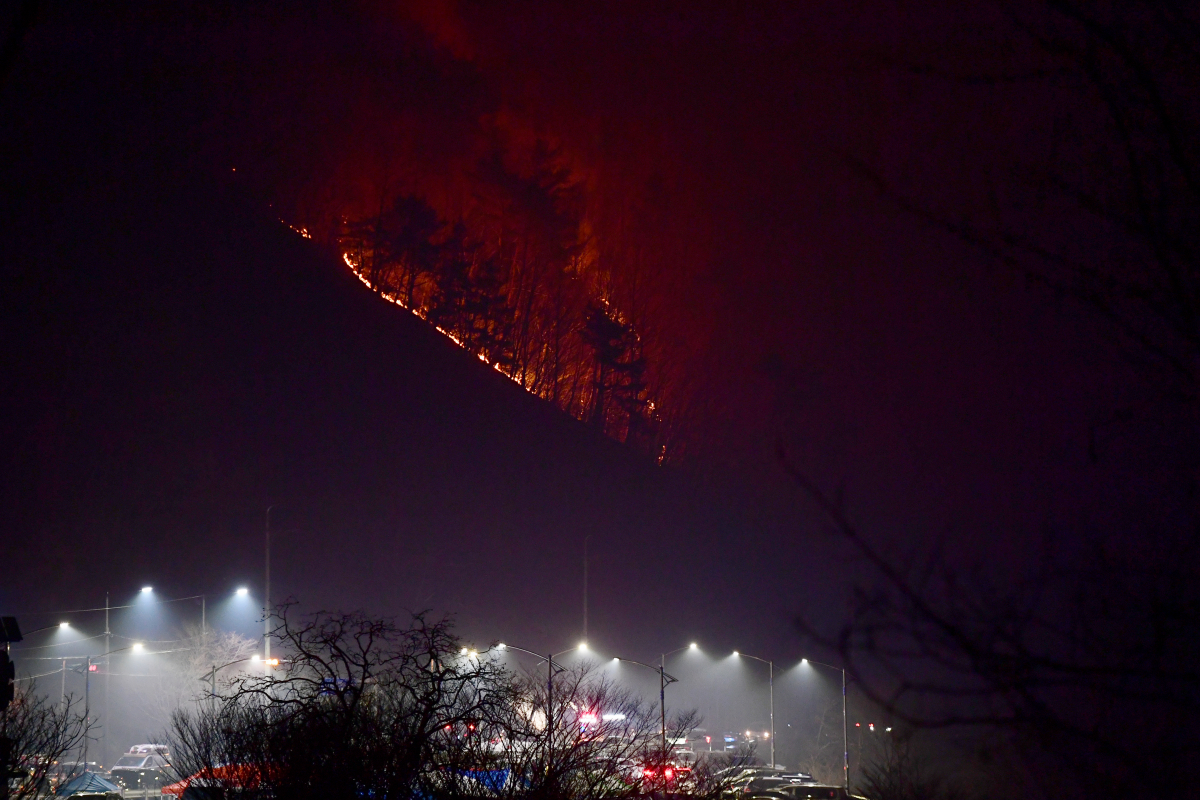 ▲3월 11일 경남 하동군 화개면 대성리 일원에서 발생한 산불이 확산되고 있는 가운데 12일 새벽 불을 밝힌 산불현장 통합지휘본부 인근 산등성이가 화염에 휩싸여 있다. (뉴시스)