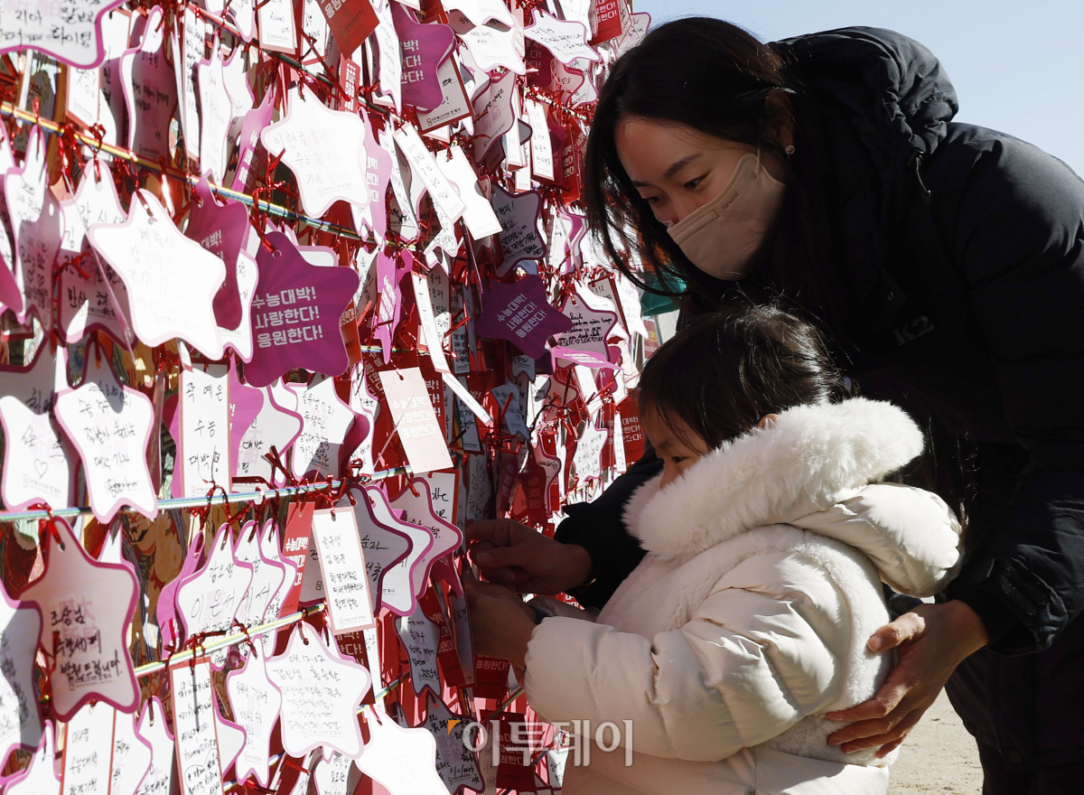 ▲2024학년도 대학수학능력시험이 나흘 앞으로 다가온 12일 서울 종로구 조계사에서 한 아이가 엄마와 수능 응원 메시지를 게시판에 붙이고 있다. 조현호 기자 hyunho@