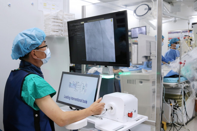 ▲서울아산병원 심장내과 이승환(왼쪽), 김태오(오른쪽) 교수팀이 국산 로봇을 이용한 관상동맥중재술을 국내 최초로 시행하고 있다. (사진제공=서울아산병원)
