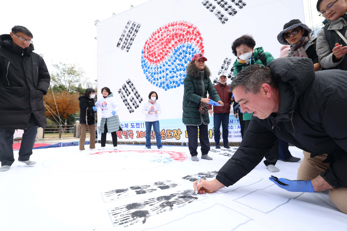 ▲26일 서울 종로구 보신각 앞 광장에서 열린 ‘대한민국 100만 손도장 태극기몹’ 캠페인에서 한 외국인이 손도장을 찍은 뒤 서명하고 있다. 신태현 기자 holjjak@