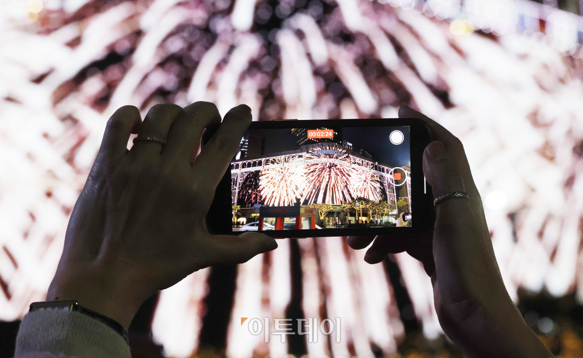 ▲성탄절을 한 달여 앞둔 28일 서울 중구 신세계백화점 본점에서 시민들이 외벽에 LED 조명으로 밝힌 미디어 파사드(Media Fasade) 크리스마스 영상을 핸드폰 카메라에 담고 있다. 신세계백화점 본점 외벽의 미디어 파사드는 375만 개의 LED 칩을 사용해 63x18m 크기의 거대한 스크린으로 탈바꿈했다. 지난해 글자를 새겼던 돌출부 발코니까지 모두 LED로 덮은 것이 특징이다. 9일 시작해 내년 1월 말까지 운영하는 미디어 파사드는 3분 가량의 크리스마스 영상이 매일 오후 5시 30분부터 10시 30분까지 반복 재생된다. 조현호 기자 hyunho@