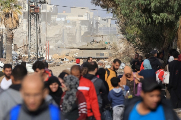 ▲19일(현지시간) 가자시티 자이툰 주민들이 피란 중인 가운데 이스라엘군 탱크가 뒤편에서 기동하고 있다. 가자시티(팔레스타인)/AFP연합뉴스 
