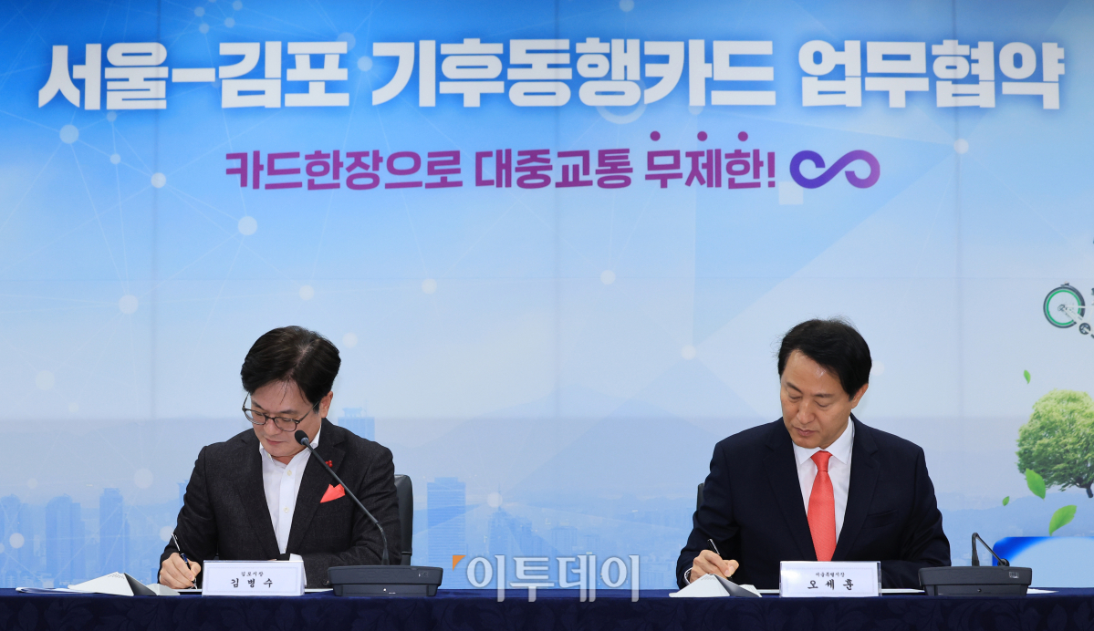 ▲오세훈 서울시장과 김병수 김포시장이 7일 오전 서울 중구 서울시청 영상회의실에서 열린 서울-김포 기후동행카드 업무협약식에서 업무협약서에 서명을 하고 있다. 조현호 기자 hyunho@