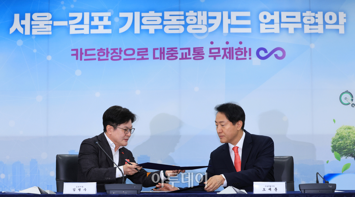 ▲오세훈 서울시장과 김병수 김포시장이 7일 오전 서울 중구 서울시청 영상회의실에서 열린 서울-김포 기후동행카드 업무협약식에서 업무협약서에 서명한 뒤 교환하고 있다. 조현호 기자 hyunho@