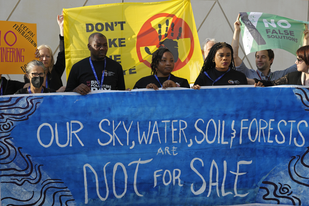 ▲8일(현지시간) 아랍에미리트(UAE) 두바이에서 열리는 제28차 유엔기후변화협약 당사국총회(COP28) 정상회의 행사장 밖에서 시위대가 “우리의 하늘과 물, 땅, 숲은 돈으로 살 수 없다”고 적힌 플래카드를 들고 서 있다. 두바이(UAE)/AP연합뉴스