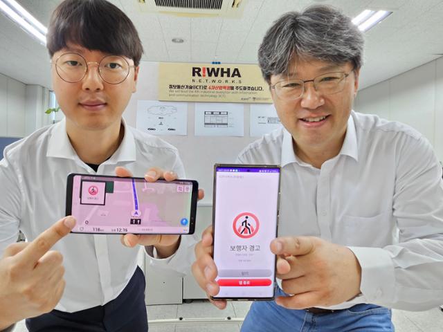 ▲이창수 이화네트웍스 기술연구소장(오른쪽)이 보행자 안전서비스 시스템 '그린사인' 서비스를 시연하고 있다. (사진제공=이화네트웍스)