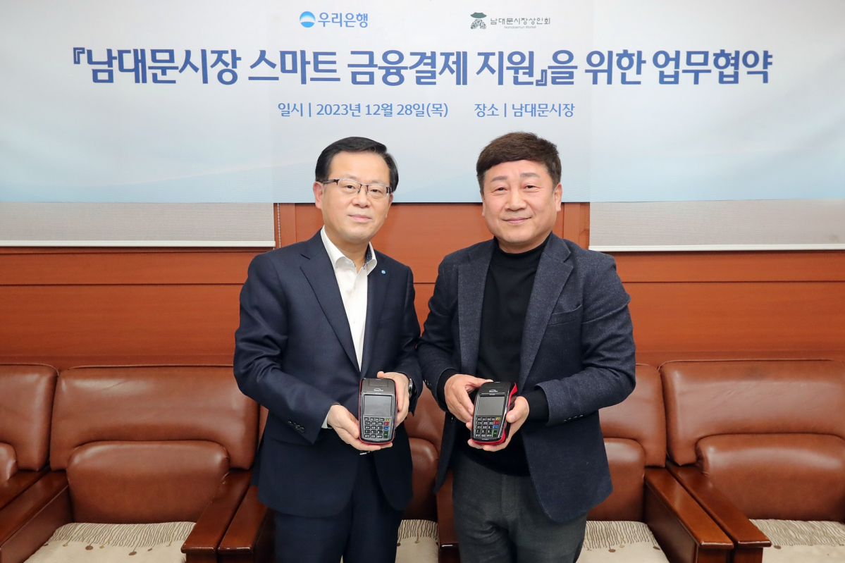 ▲우리은행은 민생금융지원방안 중 자율프로그램의 일환으로 이달 28일 남대문시장 상인회와 '상생경영 및 동반성장을 위한 협약'을 체결하고 스마트 결제기기 지원을 통해 남대문시장 스마트 결제 인프라 구축을 지원하기로 했다. 조병규 우리은행장(사진 왼쪽)과 문남엽 상인회 회장이 기념촬영을 하고 있다. (사진제공=우리금융그룹)