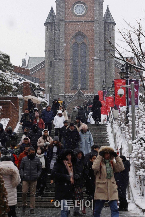 ▲서울에 눈이 내리며 2015년 이후 8년만에 화이트 크리스마스를 맞은 25일 서울 중구 명동성당에서 시민들이 눈을 피해 발걸음을 옮기고 있다. 조현호 기자 hyunho@