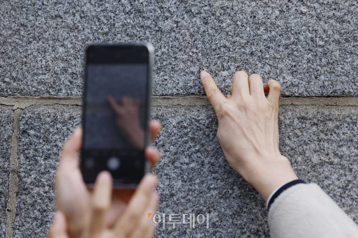 ▲4일 낙서 제거 작업을 마친 서울 종로구 경복궁 영추문 앞에서 문화재청 관계자가 담장에 희미하게 남아있는 낙서 자국을 가리키고 있다. 조현호 기자 hyunho@
