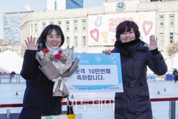 ▲23일 서울 중구 서울광장 스케이트장에서 열린 방문객 10만 명 돌파 기념 행사에서 10만 번째 방문객인 문가랑(24, 왼쪽) 씨가 관계자에게 꽃다발과 서울시 굿즈를 받은 후 기념촬영을 하고 있다. 조현호 기자 hyunho@