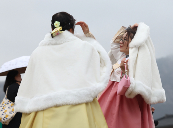 ▲21일 오후 서울 경복궁을 찾은 외국인 관광객들이 한복에 외투를 걸친 채 걸어가고 있다. (연합뉴스)