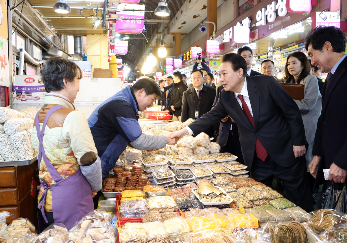 ▲윤석열 대통령이 21일 울산시 남구 신정상가시장을 찾아 옛날과자 가게에서 상인과 인사하고 있다. (연합뉴스)