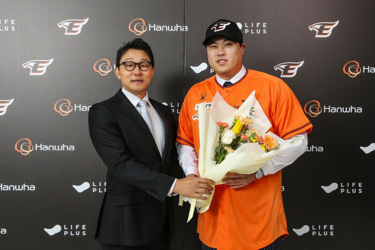▲류현진이 22일 한화 이글스와 8년 최대 총액 170억원에 계약한 뒤 박찬혁 한화 이글스 대표 이사로부터 환영 꽃다발을 받고 웃고 있다. (사진제공=한화이글스)
