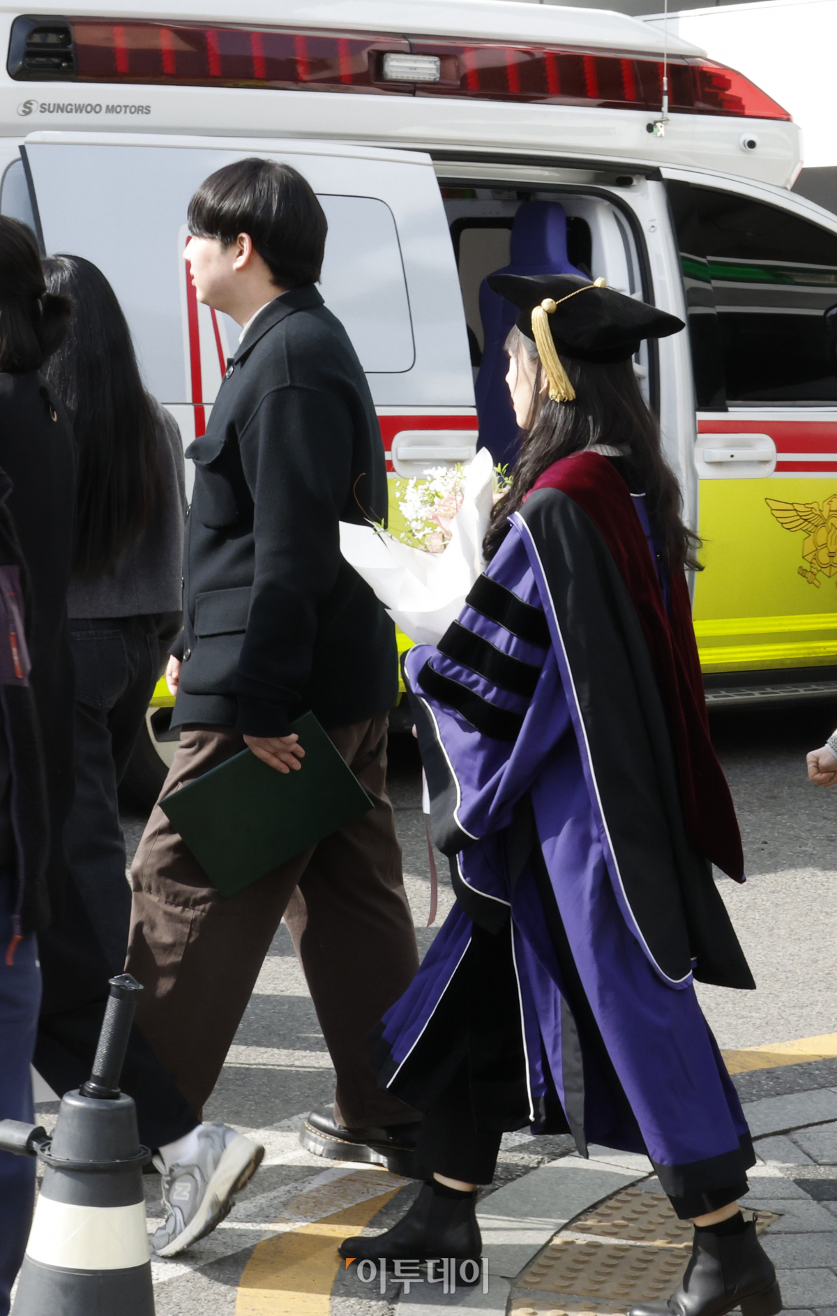 ▲27일 서울 종로구 서울대학교 연건캠퍼스 의과대학에서 열린 서울대학교 의과대학·대학원 제78회 전기학위수여식에서 학위복을 입은 학생이 앰뷸런스 앞을 지나가고 있다. 조현호 기자 hyunho@